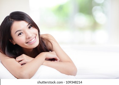 Charming woman Smile face close up and she lying on the bed in the morning with nature green background, model is a asian girl