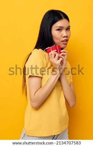 Charming young Asian woman holding a gift box in his hands posing isolated background unaltered