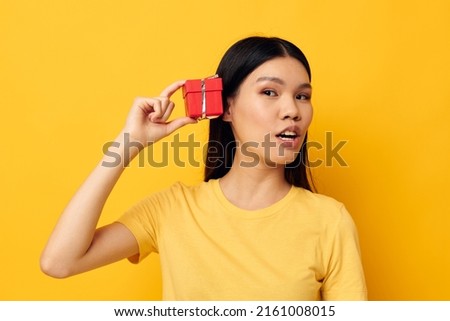 Charming young Asian woman in a yellow t-shirt holiday gift emotions studio model unaltered