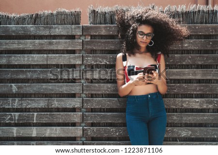 Similar – Frau mit Afro-Haaren auf der Straße, die ein Smartphone hält.