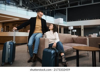 Charming young couple in love, married heterosexual couple, business partners, travelers, passengers with suitcase relaxing in the VIP lounge, waiting for flight check-in at international airport - Powered by Shutterstock