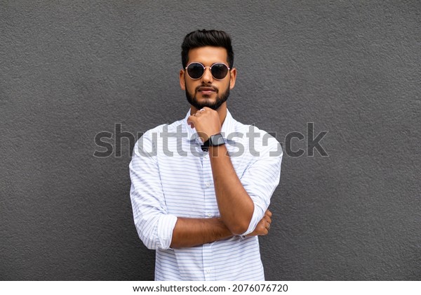 Charming young indian man in casual wear\
isolated on gray\
background