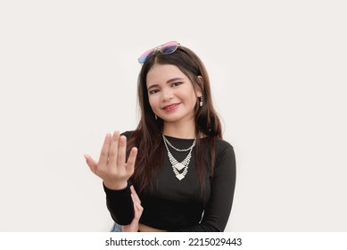 A Charming Young Lady Holds Her Palm Upside Down While Gesturing To Come Over. Studio Shot Isolated On A White Background.