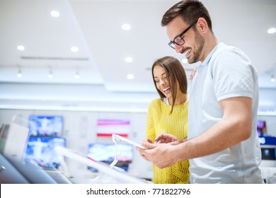 Charming young smiling love couple looking on a tablet while buying in a tech store. - Shutterstock ID 771822796