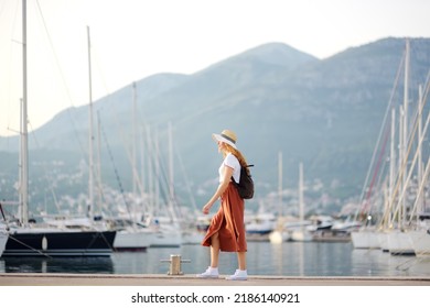 Charming Young Tourist Woman Travel By Mediterranean Coast. Attractive Red-haired Girl On The Background Of Sea And Yachts. Yacht Rental. Tourism And Travel Concept.