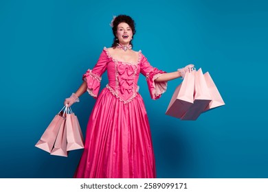 Charming young woman in an elegant baroque costume holding shopping bags against a blue background