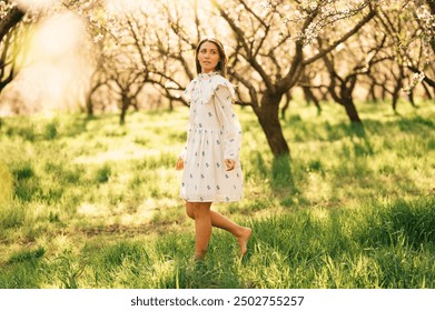 Charming Young Woman Enjoying a Serene Meadow Surrounded by Blossoming Trees and Nature - Powered by Shutterstock