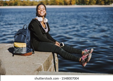 Charming young woman holding smartphone and smiling stock photo