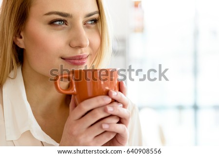 Charming young woman keeping cup of hot drink