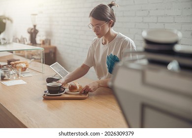 Charming Young Woman Preparing Coffee And Bun For Customer In Cafe