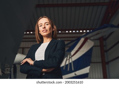 Charming Young Woman Standing In Aircraft Hangar