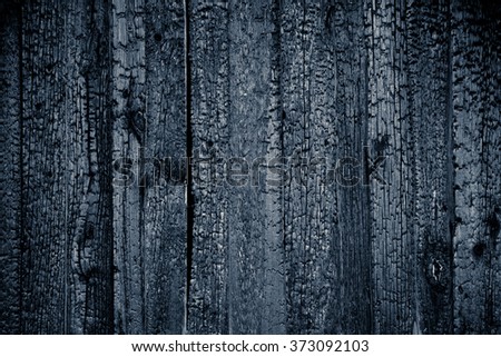 Charred black wooden wall with copy space. Abstract background with a burned boards textures closeup 