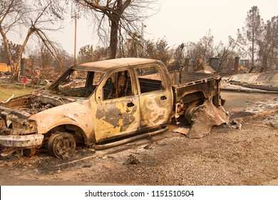 Charred Truck In Front Of Home Burned To The Ground In The Recent Wild Fire Fire Storm In Redding, California. Smoke And Ash In The Air As The Fire Continues To Burn Several Miles Away.