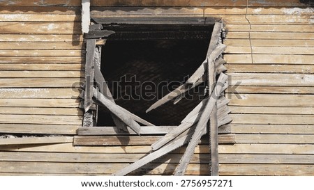 Charred window frame and broken pieces of wood on a damaged house after a fire