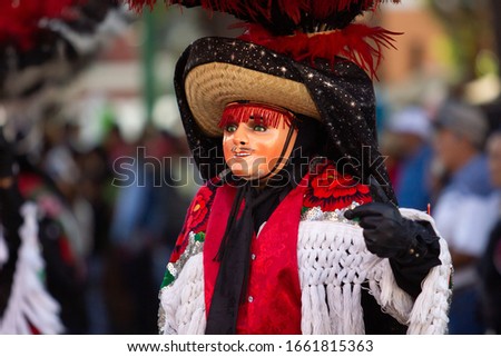 a charro dancer with black cape and red and black plumes
