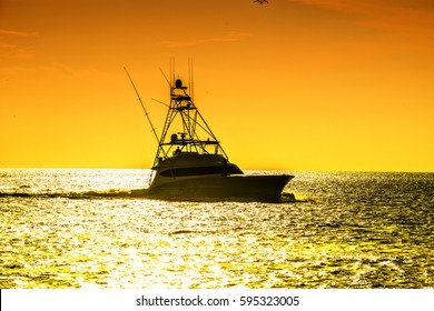 Charter Fishing Boat Against Sunset Skies Of Orange And Yellow 