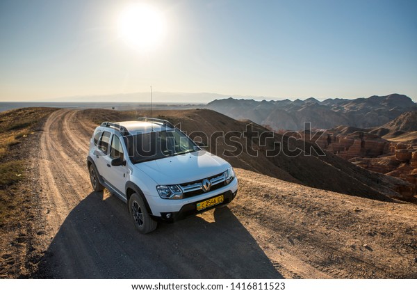 Charyn, Kazakhstan - 09.20.2017: a white 4wd\
Renault Duster (Dacia Duster) on a dirt road by the Charyn canyon\
right after the sunrise