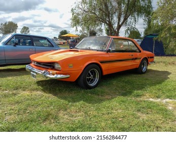 CHASCOMUS, ARGENTINA - Apr 10, 2022: Old IKA Renault Torino Lutteral Comahue Coupe 1968 - 1978 In Countryside  Classic Orange Sport Compact Car  Side View  Nature, Grass, Trees  Copyspace