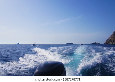 Chasing Boats On The Sea In The Summer. Outboard Motor Closeup And Trail Of Foam On The Water.