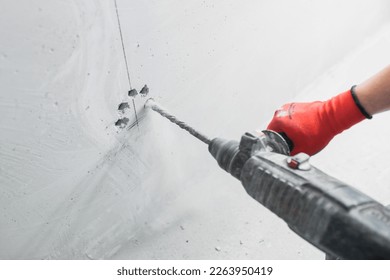 Chasing an installation channel in a concrete wall with an impact drill and attachments - dirty noisy work in finishing - Powered by Shutterstock