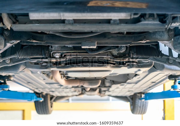 chassis\
bottom view and power steering rack and suspension system of saloon\
or sedan car at garage lift up for\
maintenance