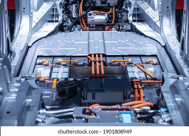 Chassis Of The Electric Car With Powertrain And Power Connections Closeup. Blue Toned. EV Car Drivetrain At Maintenance