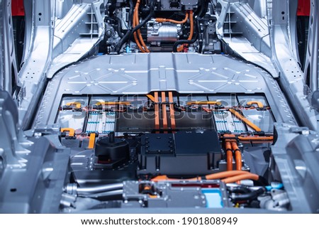 Chassis of the electric car with powertrain and power connections closeup. Blue toned. EV car drivetrain at maintenance