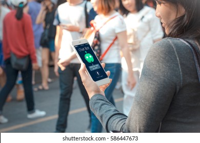 Chat Bot Concept.Young Female Hands Holding Mobile Phone On Blurred People Walking As Background