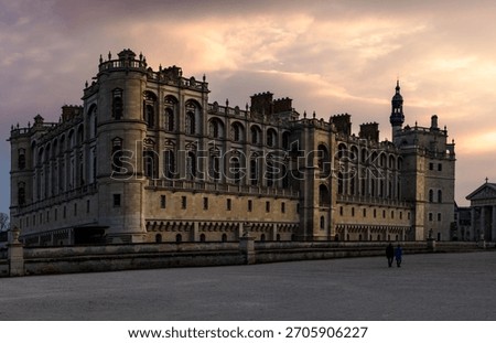 Chateau de Saint-Germain-en-Laye at sunset with dramatic sky and two people walking, France