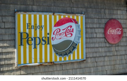Chatsworth, Georgia USA - January 06, 2018  An old large pepsi sign with a soda cap and a round smaller coca-cola sign side by side on the back wall of a building outdoors
