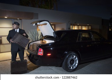 Chauffeur Loading Luggage In Car At Night
