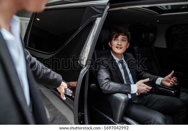chauffeur\
opeing the car door for his boss to come\
out.