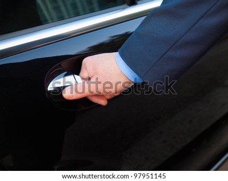 Chauffeur's hand opening passenger door on limousine