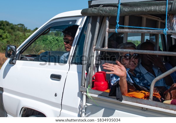 Chaung Thar, Myanmar - December 26,\
2019: An older unidentified woman in sunglasses waves from the back\
of a truck on December 26, 2019 in Chaung Thar,\
Myanmar