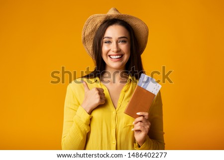 Cheap Flight Deals. Girl Holding Tickets And Passport Gesturing Thumbs-Up On Yellow Studio Background. Copy Space