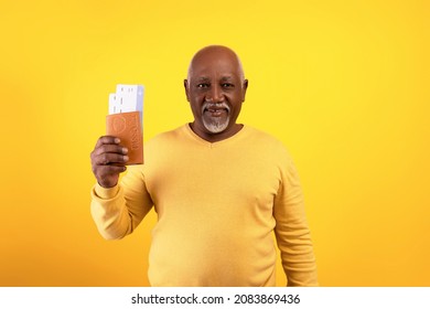 Cheap Flights Concept. Happy Senior Black Man Holding Passport And Tickets, Standing On Orange Studio Background. Joyful Elderly Male Going On Vacation, Travelling Abroad