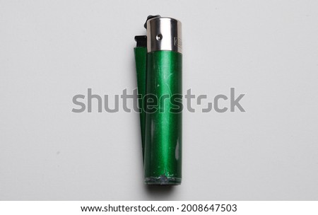 cheap green plastic gas disposable cigarette lighter on wooden surface closeup 