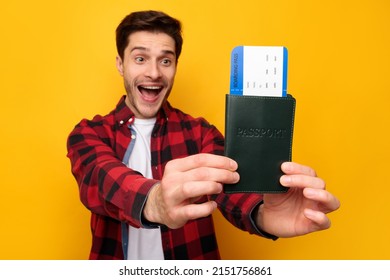 Cheap Tickets Concept. Portrait Of Excited Guy Holding Showing Boarding Pass And Passport Standing On Yellow Studio Background. Joyful Male Tourist Ready For Travel. Book Your Trip