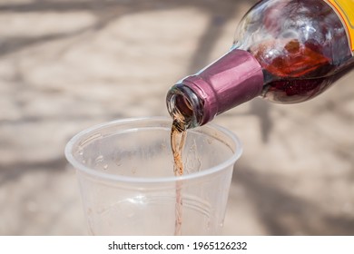 Cheap Wine Pouring From A Bottle Into A Plastic Glass