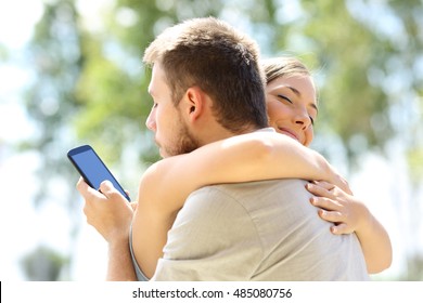 Cheater Texting With His Other Lover On Phone And Hugging His Innocent Girlfriend