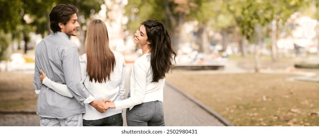 Cheating Husband Holding Hands With Wife's Best Friend Walking Together In Park Outside. Love Triangle Concept. Rear View - Powered by Shutterstock