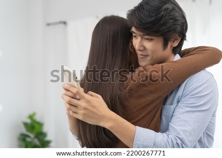 Cheating on girlfriends concept, unfaithful Asian man looking at mobile phone text during embracing with his lover