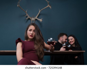 Cheating Relationships. Sad Betrayed Girl. Love Affair Behind Back, Male Cheater With Friend. Unfaithful Partner, Pretty Female With Horns On Blue Background In Focus On Foreground