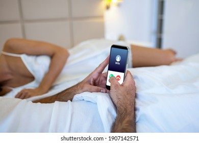 Cheating Unfaithful Man Lying With Mistress In Hotel Bed. Call From Wife To Mobile Phone. Cheater Having Affair With Secret Lover And Relationship With Another Woman. Infidelity And Love Triangle.