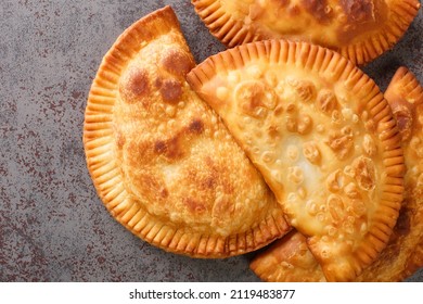 Chebureki is a deep-fried turnover with a filling of ground or minced meat and onions close up in the table. Horizontal top view from above