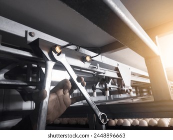 Check and adjusting the turning sensor on the incubation hatchering machine. Twchnician adjusting turning sensor with tools wrench.