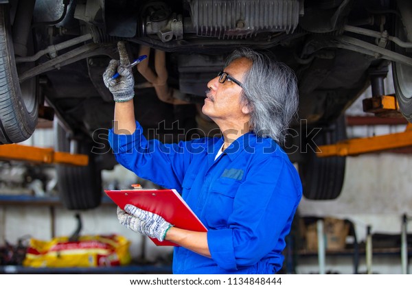 check the condition of the car engine and\
oil / man hand holding\
\
clipboard.