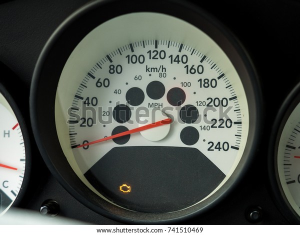 Check engine light. Car dashboard in\
closeup. White Car\
speedometer.