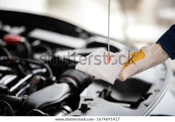 Check engine oil level Close up hands checking\
lube oil level of car engine from deep-stick for service and\
maintenance concept.