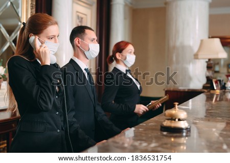 Check in hotel. receptionist at counter in hotel wearing medical masks as precaution against virus.  商業照片 © 
